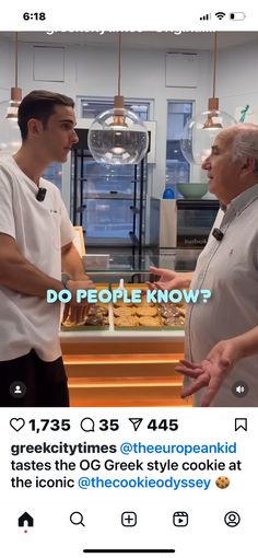 two men are talking to each other in front of a bakery counter with donuts on it