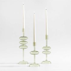 three glass candlesticks sitting next to each other on top of a white surface