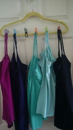 four different colored bras hanging on a hook in front of a door with hooks