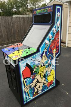 an arcade machine sitting on top of a parking lot next to a fence and house