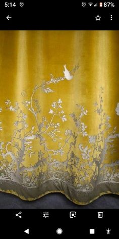 a yellow curtain with white flowers and birds on it