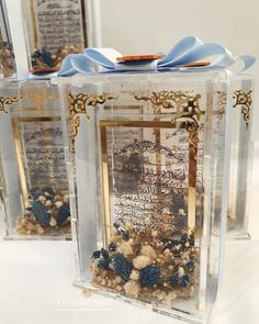 two clear boxes with blue ribbons and pictures inside