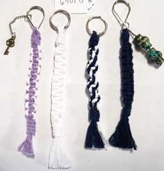 four different types of key chains hanging from hooks on a white surface with a price tag attached to them