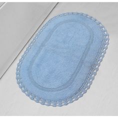 an oval blue rug on top of a white bed sheet with lace trimmings