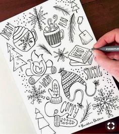 a person is holding a marker and drawing christmas doodles on a piece of paper