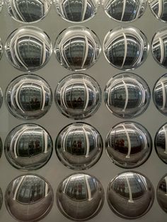 many shiny glass balls are arranged on a wall