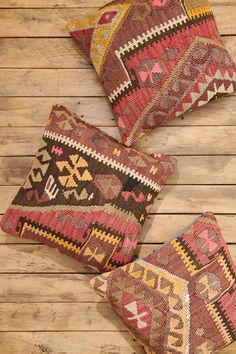 three colorful pillows sitting on top of a wooden floor