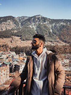 a man standing on top of a balcony next to a mountain