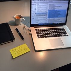 an open laptop computer sitting on top of a desk next to a cup of coffee