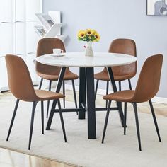 a white table with four brown chairs around it and a vase filled with yellow flowers