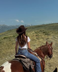 a woman riding on the back of a brown and white horse