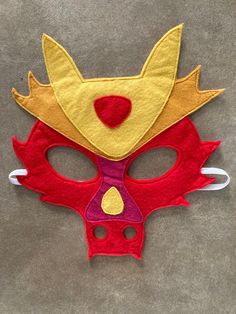 a red and yellow mask with horns on the face is sitting on a gray surface