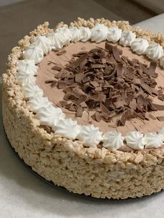 a cake with white frosting and chocolate shavings on top is sitting on a table