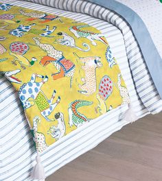 a bed with yellow and blue sheets on top of it next to a wooden floor