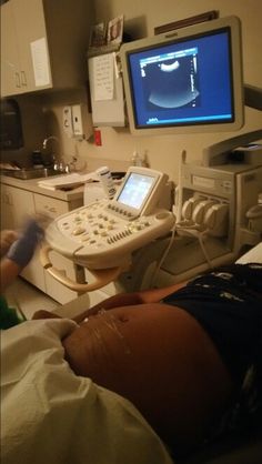 a person laying down in a hospital bed next to a monitor and other medical equipment