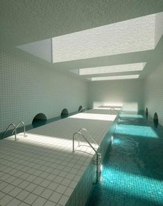 an indoor swimming pool with sun shining through the ceiling and tiled walls on both sides