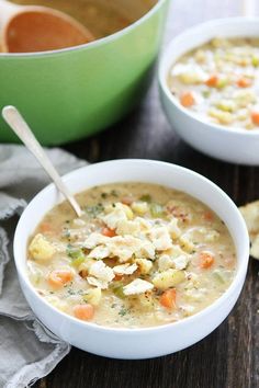 two bowls filled with soup on top of a wooden table