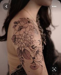 a woman's arm with flowers and leaves tattooed on her shoulder, in black and white