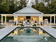 an outdoor pool with lights around it and seating area next to the pool is surrounded by greenery