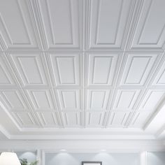 a living room filled with lots of furniture and white ceiling tiles on top of the walls