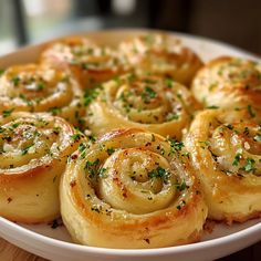 a white plate topped with rolls covered in cheese and parmesan sprinkles