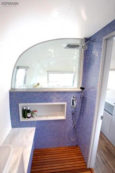 a bathroom with blue and white tiles on the walls, wood flooring and a shower head