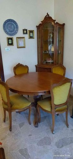 a dining room table with yellow chairs and a china cabinet in the corner behind it