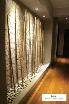 a wall with some rocks and bamboo sticks on it in front of a wooden floor