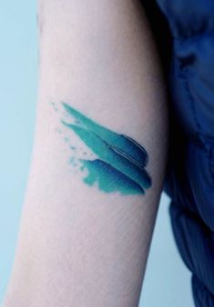 a woman's arm with a blue inked surfboard tattoo on the left forearm