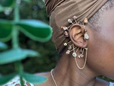 a close up of a person with ear rings and jewelry on her head wearing a brown top