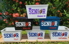 four coolers are stacked on top of each other in front of some bushes and flowers