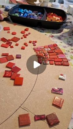 a person is making red glass mosaics on a table