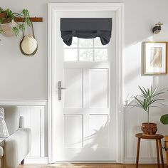 a living room with a white door and potted plants on the wall next to it