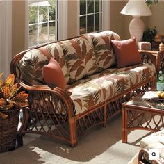 a living room with wicker furniture and plants in the centerpieces on the coffee table