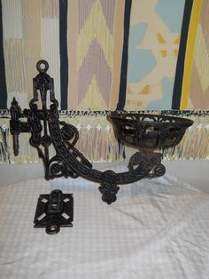 an iron candelabra next to a wallpapered background with decorative designs