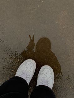 a person standing in the water with their shadow on the wet ground next to them