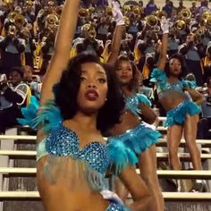 a group of cheerleaders are in the stands at a football game with their hands up