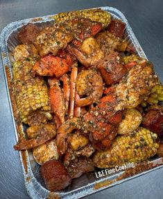 cooked lobster and corn on the cob in a foil container with seasoning sprinkles