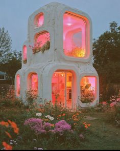 a house made out of concrete with plants growing on the outside and windows lit up at night