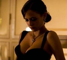 a woman in a black dress looking down at her cell phone while wearing a necklace