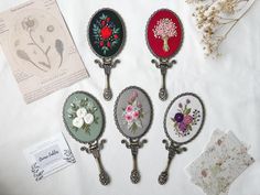 four different types of flowers are displayed on a table with papers and buttons in the background