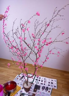 a vase with pink flowers sitting on top of a table next to papers and cups