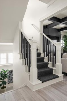 a white staircase with black railings and carpeted steps in a home, next to a couch