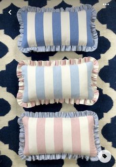 three blue and pink pillows sitting on top of a rug