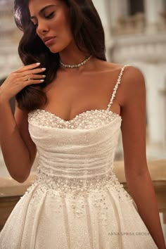 a woman in a wedding dress posing for the camera with her hand on her shoulder