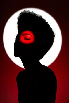 the silhouette of a woman with an eyeball in front of a white and red moon