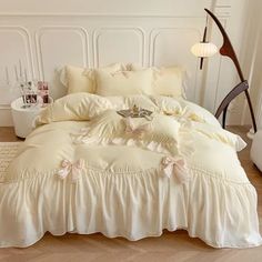 a white bed with ruffled bedspread and pillows on the floor in a room