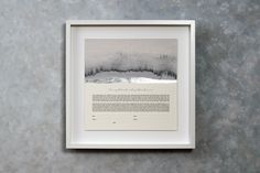 a white frame hanging on the wall above a framed print with an image of trees