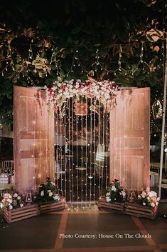 an outdoor ceremony area with flowers and greenery on the wall, decorated with wooden crates