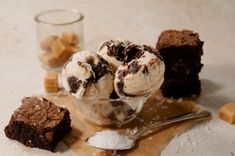 three scoops of ice cream sit in a bowl with brownies and marshmallows